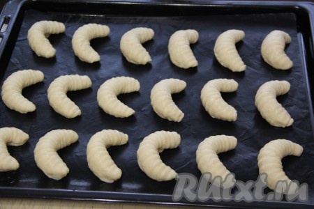 Слегка согнуть рулетик, придав форму полумесяца. Противень застелить пергаментом (или тефлоновым ковриком). Выложить печенье на противень. Аналогично сформировать все заготовки творожного печенья и выложить их на противень, оставляя между расстояние между печенюшками.