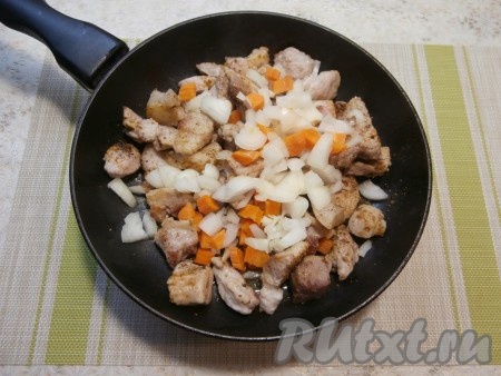 Когда кусочки свинины подрумянятся, выложить к ним нарезанный произвольно лук и нарезанную кубиками морковь.
