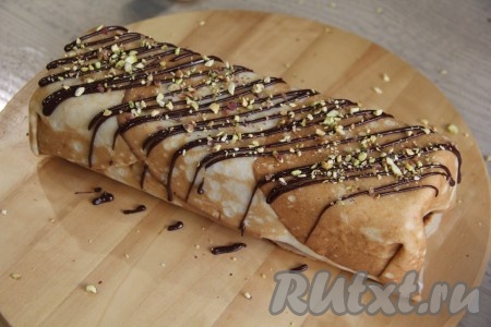 Накрыть форму плёнкой и поставить в холодильник на ночь. Готовый блинный торт достать из формы, убрать плёнку и переложить на тарелку или доску. Я дополнительно украсила верх тортика, растопив пару долек шоколада и сделав решётку поверх торта, а затем посыпала дроблёными фисташками.