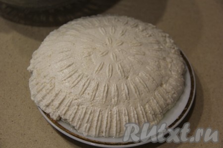 Оставить минут на 5, чтобы слилась лишняя сыворотка, затем положить поверх массы тарелочку и перевернуть будущий сыр в эту тарелочку. После этого с помощью второй тарелки перевернуть массу на другую сторону.