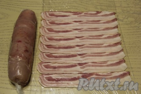 Свернуть куриное филе с помощью пищевой плёнки в ровный рулет. Взять ещё кусок плёнки, выложить на неё тонко нарезанные полоски бекона в внахлёст, как на фото.