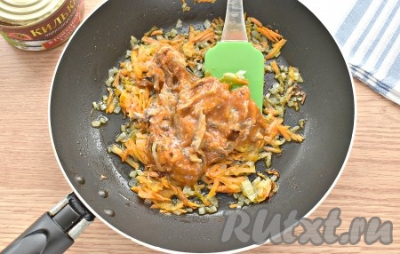 К обжаренным овощам выкладываем из баночки консервированную кильку вместе с томатным соусом, перемешиваем и тушим 5 минут, иногда помешивая.