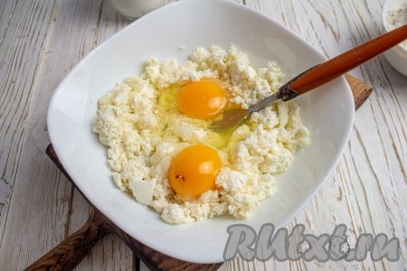 В творог с сахаром вбейте куриные яйца и перемешайте массу вилкой.