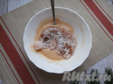 На отдельную тарелку насыпать две столовые ложки муки, обвалять в этой муке куриные отбивные со всех сторон. Затем отбивные, покрытые мукой, поместить в кляр.