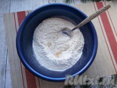 Муку просеять в объёмную миску, влить одну чайную ложку растительного масла и, понемногу вливая солёную воду, начать замешивать тесто ложкой. Потом продолжить замешивать тесто для вареников руками.