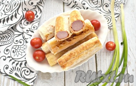 Аппетитные сосиски с сыром в лаваше подавать к столу горячими. Такая закуска прекрасно утолит голод и порадует приятным вкусом, попробуйте!