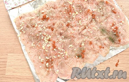 Заготовку для рулета солим по вкусу, посыпаем любимыми специями (в качестве специй я использовала чёрный молотый перец, 0,5 чайной ложки паприки, 0,5 чайной ложки сушёного укропа и 0,5 чайной ложки сушёного базилика). Равномерно распределяем по поверхности мяса нарезанный чеснок.