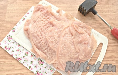 Теперь каждый пласт кладём на разделочную доску, накрываем мясо пищевой плёнкой (или одноразовым целлофановым пакетом) и отбиваем молоточком для мяса. Не переусердствуйте, пласты не должны порваться.