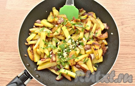 В конце приготовления добавляем к картошке измельчённый чеснок, нарубленную зелень (у меня – петрушка). Перемешиваем и жарим ещё 3 минутки.