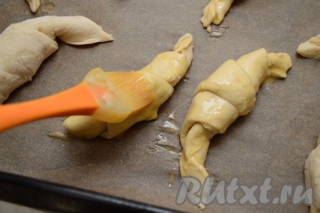 Аккуратно кулинарной кистью смажем поверхность каждого круассана взбитым яйцом.