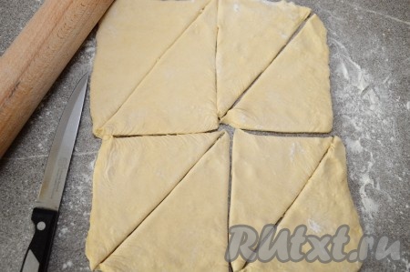 Пласт теста, на присыпанной мукой поверхности, раскатываем скалкой в прямоугольник. Раскатываем совсем немного, толщина теста должна быть, примерно 3-4 мм. Я раскатала в прямоугольник со сторонами 24 на 20 см. Прямоугольный пласт разделяем ножом на 4 примерно одинаковых прямоугольника и каждый из них разрезаем по диагонали. У нас получится 8 треугольников.