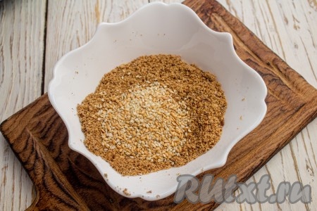 Крошку из пряников и орехов выложите в мисочку, добавьте кунжут и перемешайте.