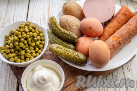 Подготовьте все необходимые ингредиенты для приготовления классического салата "Оливье" с колбасой и солёными огурцами. Заранее отварите в кожуре морковь и картофель (на отваривание этих овощей обычно требуется минут 25-30 с начала кипения воды), затем слейте воду и дайте им остыть. Яйца сварите вкрутую (варить нужно минут 8-10 после начала кипения воды), затем остудите их. Очистите варёные овощи и яйца.