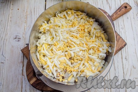 Замаринованный лук откиньте на сито, чтобы стекла лишняя жидкость, а затем выложите поверх селёдки. Сверху натрите варёные куриные яйца, разровняйте.