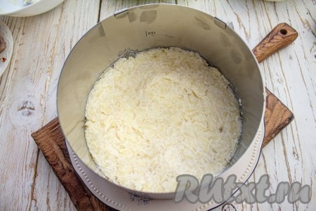 На плоское блюдо установите кулинарное разъёмное кольцо диаметром 16-18 см. Первым слоем выложите картофель и хорошо утрамбуйте.