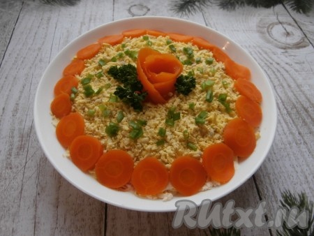 Желтки натереть на тёрке и покрыть ими верх салата. Этот слой майонезом не смазывать. Украсить салат "Мимоза" кружочками оставшейся моркови, розочкой из морковки, зелёным луком и петрушкой. 