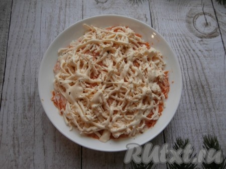 Плавленый сырок слегка подморозить в морозилке, а затем натереть его на крупной тёрке, выкладывая следующим слоем, поперчить, смазать майонезом.
