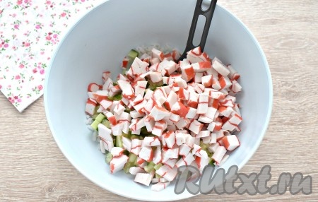 Сюда же выкладываем и крабовое мясо, нарезанное на маленькие кубики.