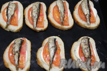 Поверх помидора выложить по одной шпротинке. 