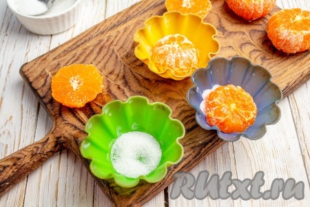 На дно силиконовых формочек для кексов (я выпекала в 10 формочках) всыпьте по чуть-чуть отложенные 30 грамм сахара. Срезом вниз вставьте половинки мандаринов. Если используете не силиконовые формы, то предварительно смажьте их растительным (или сливочным) маслом и дополнительно присыпьте мукой.