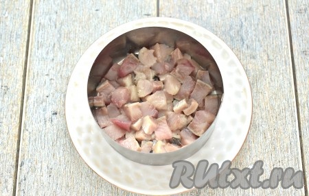 Салат выкладывается слоями. Готовить его можно в глубоком салатнике или порционно, используя креманки, или, как в моём случае, с помощью сервировочного кольца. Из указанного количества ингредиентов я готовила 3 порции салата, пропорционально раскладывая ингредиенты в сервировочные кольца. Итак, ставим сервировочное кольцо на плоскую тарелку. Филе селёдки хорошо осматриваем, удаляя косточки, если они есть. Селёдочку нарезаем на маленькие кубики и выкладываем первым слоем.