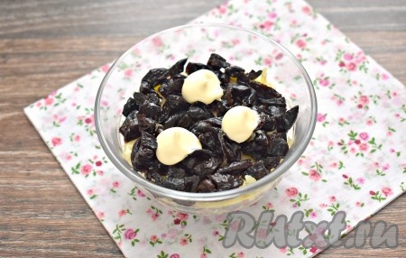 Каждый обсушенный чернослив разрезаем пополам или на 4 кусочка. Формируем слой из чернослива. Этот слой тоже смазываем майонезом.