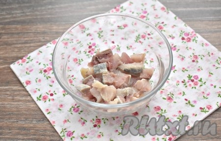 Прежде всего отвариваем по отдельности картошку и свеклу в кожуре в подсоленной воде (на варку картофеля с момента закипания воды потребуется минут 20-25, а на отваривание свеклы уйдёт минут 40-50 после начала кипения воды). Отваренные овощи после остывания очищаем. Если в филе сельди есть косточки, удаляем их. Луковицу очищаем. Чернослив на 2-3 минуты заливаем кипятком, затем промываем его под проточной водой и обсушиваем. Теперь можно приступать к непосредственному формированию салата "Селёдка под шубой". Количество ингредиентов рассчитано на две порции салата, я готовила в двух порционных креманках. Филе сельди нарезаем кубиками и выкладываем  в салатник первым слоем (если вы, как и я, готовите порционно, раскладывайте ингредиенты по двум салатникам).