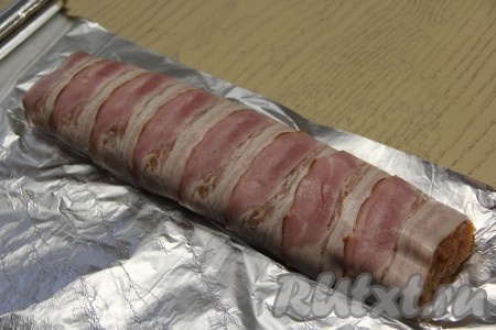 Помогая пищевой плёнкой, завернуть колбаску из куриного фарша в бекон. Вся начинка из фарша должна быть внутри бекона. Переложить рулет на лист фольги.