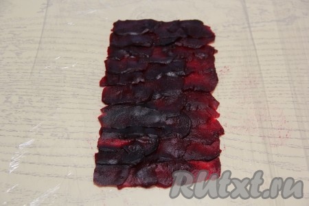 1-1,5 свеклы с помощью овощечистки нарезать на тонкие полоски - слайсы. Если вы нарежете 1,5 свеклы - рулет получится большего размера, если свекла достаточно крупная, то можно и одну свеколку нарезать на слайсы. Выложить на пищевую плёнку внахлёст слайсы свеклы в форме прямоугольника.&nbsp; 