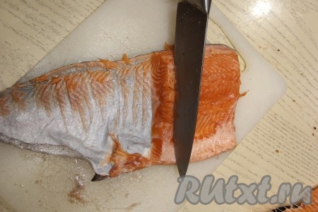 У форели удалить голову и хвост, срезать кухонными ножницами нижние плавники. Разрезать рыбу по хребту вдоль и отделить хребтовую кость. Голову, хребет, хвост и плавники можно заморозить и использовать в дальнейшем для приготовления рыбного супа. После разделки получатся 2 рыбных филе, аккуратно удалить оставшиеся мелкие косточки. Острым ножом нарезать филе форели на тонкие ломтики, дорезая до кожи и срезая тонкие ломтики филе (таким образом кусочки форели уже будут очищены от кожи).