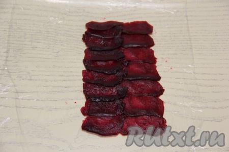 На столе (или на разделочной доске) расстелить пищевую плёнку. Свеклу почистить и с помощью овощечистки нарезать на тонкие полоски - слайсы. Выложить слайсы свеклы на пищевую плёнку внахлёст в виде прямоугольника. Я формировала 2 ролла, поэтому на плёнку выложила в виде прямоугольника вначале одну свеклу, нарезанную на слайсы.