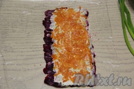 Следующим слоем равномерно выложить натёртую морковку, не забывая, что один край остаётся свободным.