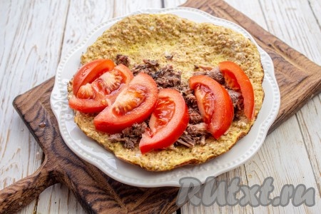 На половину блина разложите консервированного тунца, сверху на рыбу выложите нарезанный на дольки помидор.
