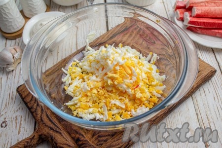 Куриные яйца отварите вкрутую (варим 8-10 минут с момента начала кипения), охладите, очистите и натрите на средней тёрке в глубокую миску.