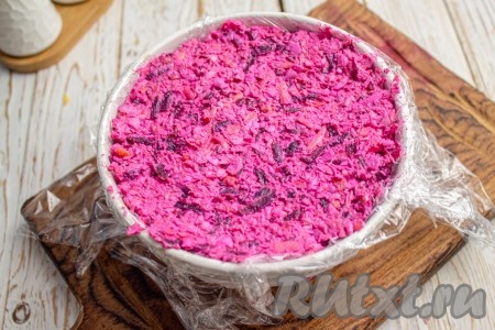 Я решила подачу салата "Розовый фламинго" сделать в виде полукруглой горки, для этого я выстелила подходящую по размерам мисочку плёнкой так, чтобы края плёнки свисали с краёв миски. В мисочку, застеленную плёнкой, выложила салат и утрамбовала. Краями плёнки накрыла верх салата и убрала в холодильник на минут 30.