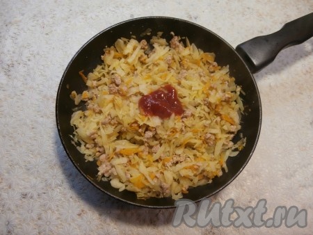 Влить воду, аккуратно перемешать. Накрыть сковороду крышкой и тушить капусту с фаршем на небольшом огне 15 минут, иногда перемешивая (капуста должна стать достаточно мягкой). Затем добавить 1 столовую ложку томатного соуса (или кетчупа), перемешать.