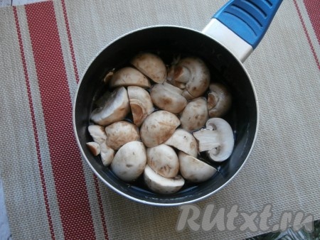Шампиньоны промыть, удаляя загрязнения. Если грибочки крупные, их нужно разрезать на 2-4 части. Мелкие грибы резать на части не нужно. Подготовленные шампиньоны переложить в кастрюлю, залить полностью водой, поставить на огонь, а после закипания отварить грибочки в течение 10-15 минут. Затем слить воду, дать отваренным грибам остыть.