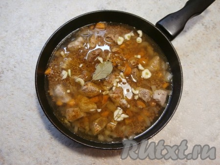 Влить горячую воду, посолить и поперчить, всыпать специи, добавить нарезанный чеснок и лавровый лист.