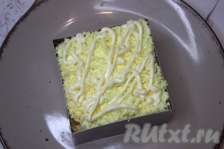 Далее вложить натёртый на тёрке желток (оставить немного желтка для украшения салата), нанести сеточку из майонеза.