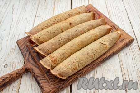 Сверните блин с начинкой в рулет. Таким образом подготовьте все рулеты.