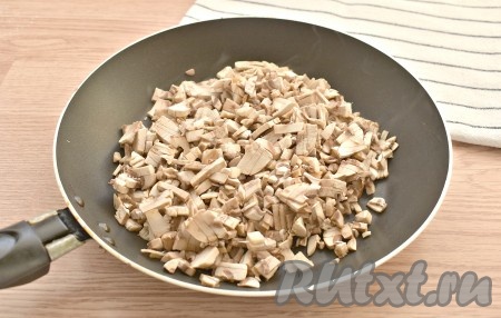 Промываем заранее свежие шампиньоны, чтобы они перед жаркой успели немного обсохнуть. Нарезаем грибы на мелкие кусочки. На плиту ставим сковороду, делаем сильный нагрев. Поверхность сковороды смазывать ничем не нужно. Выкладываем в сковороду нарезанные грибы.