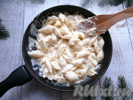 Добавить в сырно-сливочный соус макароны, хорошо смешать макароны с соусом.