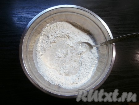 Сделать небольшое углубление и постепенно вливать тёплую воду (температура воды должна быть около 40 градусов), замешивая ложкой тесто.