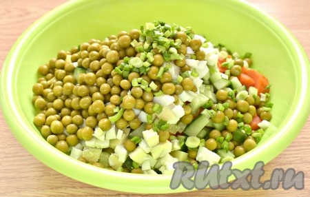 С зелёного горошка сливаем жидкость, переложив его на сито. Зелёный лук промываем, нарезаем, а затем вместе с горошком добавляем в салат.
