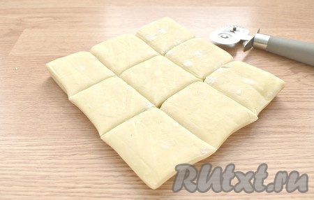 Для выпечки тарталеток я использовала качественное (проверенное мной много раз в деле) тесто (два пласта, каждый размером 18 см на 18 см). Не разъединяя пласты, я нарезала тесто на квадраты размером 6 см на 6 см. Всего получилось 18 квадратов. Для нарезки я взяла пиццерезку. Если боитесь, что пласты прилипнут друг к другу, то лучше нарезать их по отдельности. При необходимости тесто можно чуть-чуть раскатать в одном направлении.