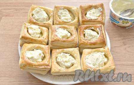 Тарталетки из слоёного теста остужаем. Заполняем их творожным сыром. На одну тарталетку достаточно чайной ложки сыра.