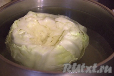 В большой кастрюле вскипятить подсоленную воду, уменьшить огонь. В эту кастрюлю поместить кочан капусты, проварить минут 5-7, верхние капустные листья станут эластичными и мягкими.