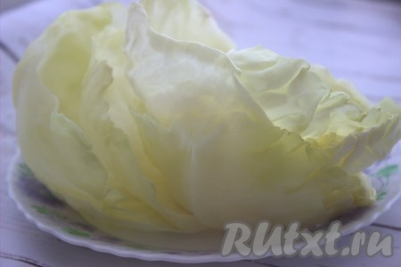 При помощи двух вилок аккуратно отделить несколько верхних капустных листов, ставших эластичными, и переложить на тарелку. Кочан снова отправить в кастрюлю и снова проварить, чтобы верхние листья стали эластичными, отделить их от кочана, переложить на тарелку. Постепенно подготовить так все листики. С каждого отваренного капустного листа ножом срезать утолщенную прожилку, находящуюся на внешней стороне листика (срезая прожилку, не повредите сам лист, он должен остаться целым). 10 подготовленных листов нам будут нужны для формирования голубцов. Остальные листики нам понадобятся в процессе томления голубцов в духовке.