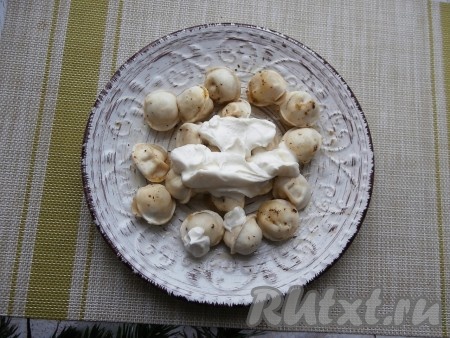 Добавить к пельменям сметану, перемешать их.