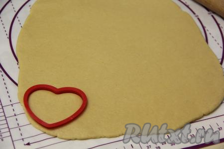 На слегка присыпанной мукой поверхности тесто раскатать в пласт толщиной, примерно, 0,5 см. Затем с помощью вырубки в форме сердечка вырезать заготовки печенья. Если вырубки у вас нет, то можно вырезать сердечки острым ножом.